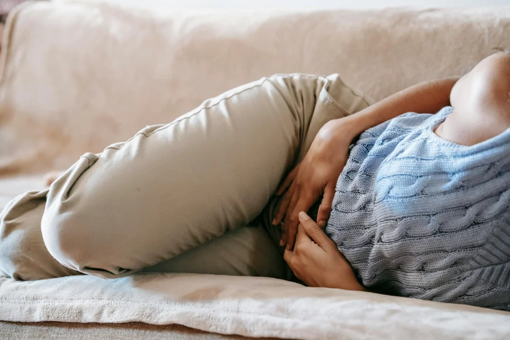 A person lying on the couch holding their stomach.