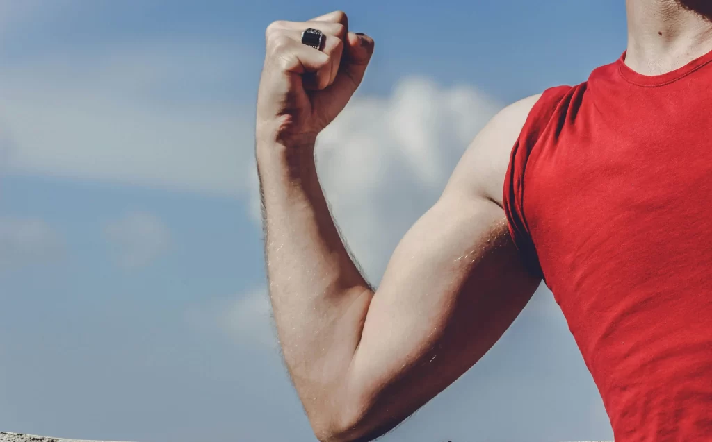 A person in a red muscle shirt flexing their biceps.