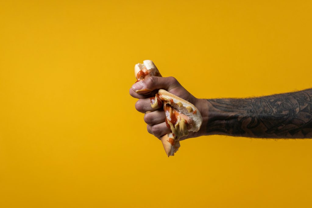 Person crushing a hotdog in their hands