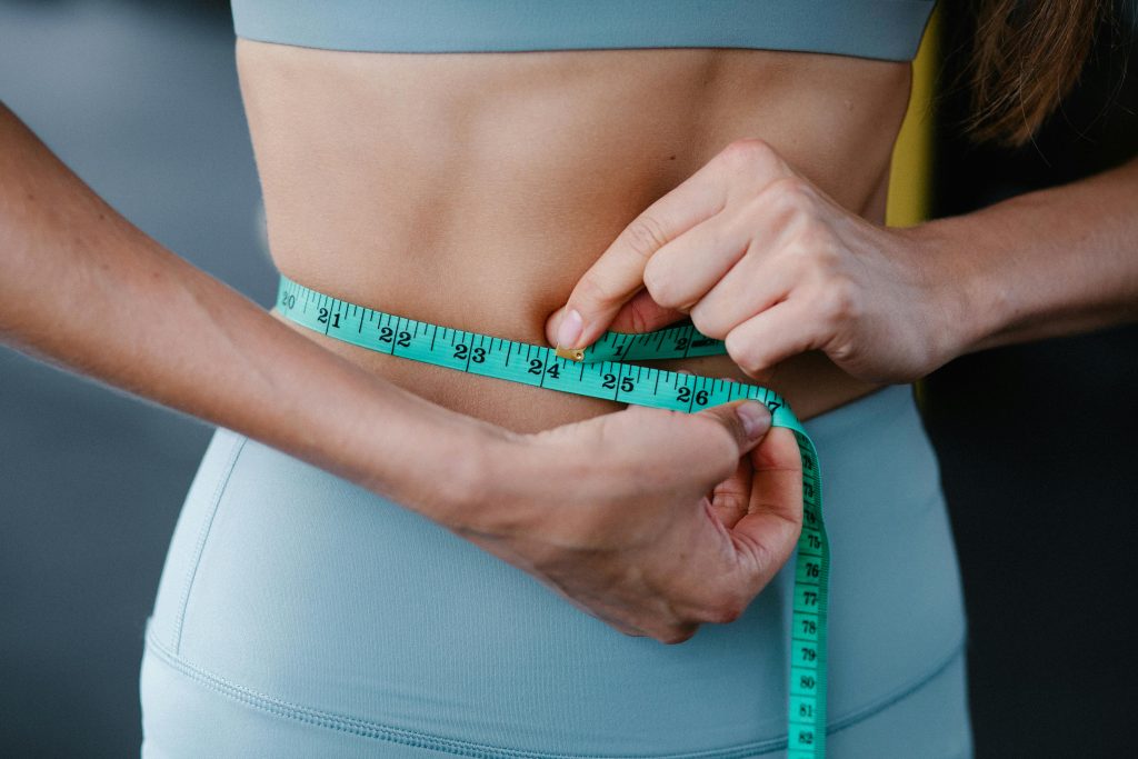 Person measuring waist for weight loss
