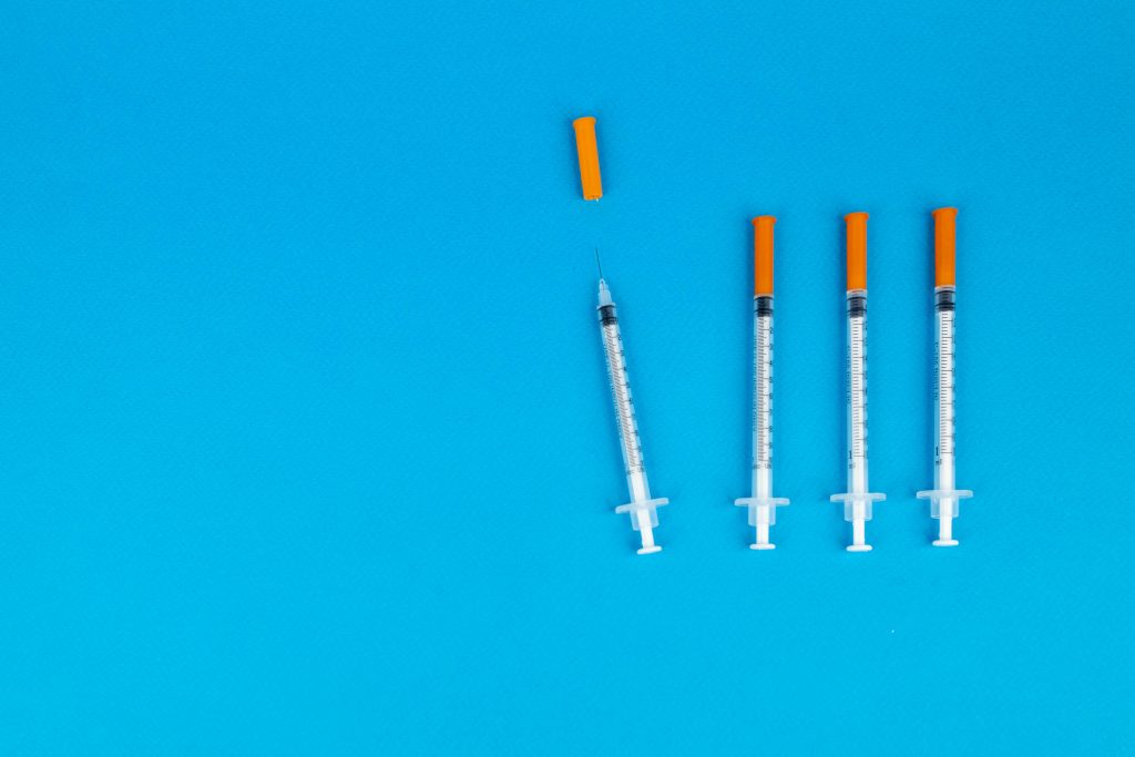 4 syringes on a blue background